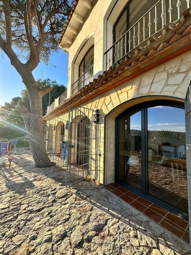 Andalusische Finca im Abendlicht, in der Natursteinfassade sitzen neue Bogenfenster mit anthrazitfarbenem Rahmen
